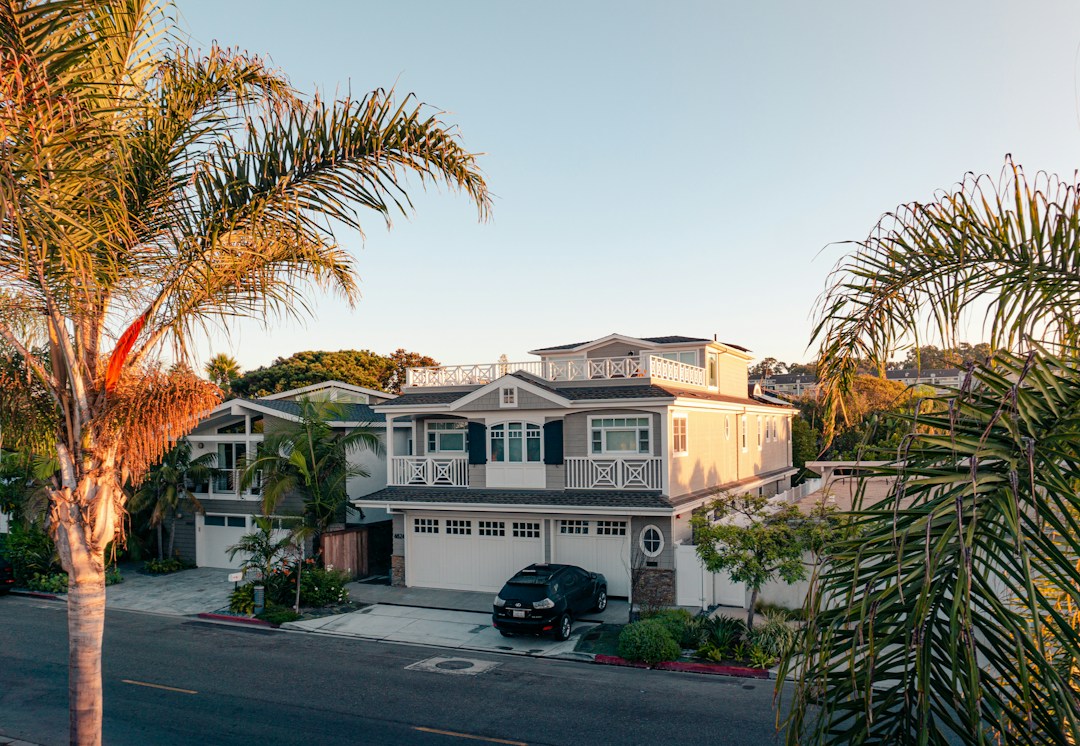 White two-story house surrounded by green trees